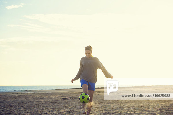 Spain  Young woman playing soccer at the beach