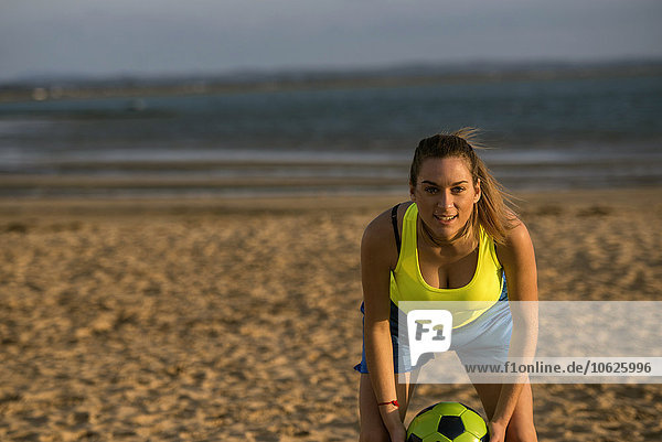 Spanien  Junge Frau spielt Fußball am Strand