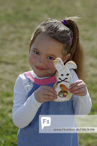 Portrait of smiling little girl showing pastry formed like an Eastern Bunny