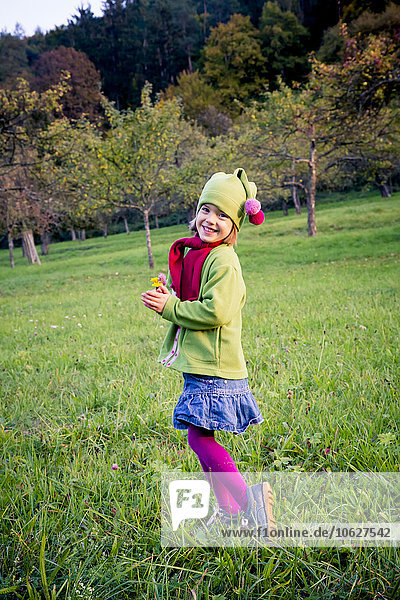 Deutschland  Baden-Württemberg  lächelndes kleines Mädchen auf einer Wiese im Herbst