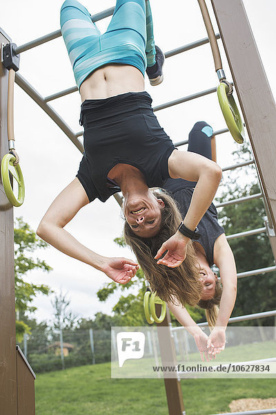 Two women having fun hanging in jungle gym