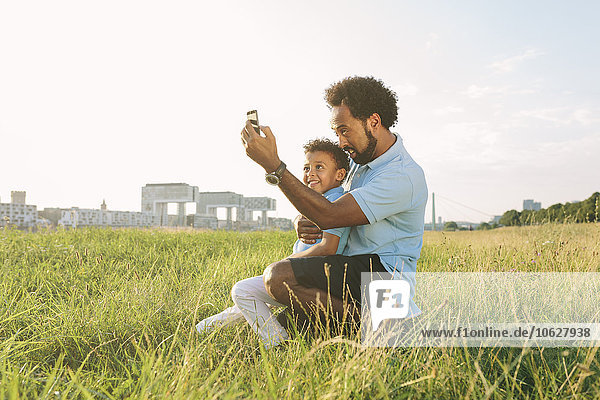 Deutschland  Köln  Vater und Sohn in einem Feld  das einen Selfie nimmt.