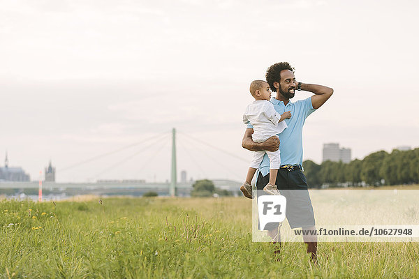 Deutschland  Köln  Vater trägt seinen Sohn im Feld