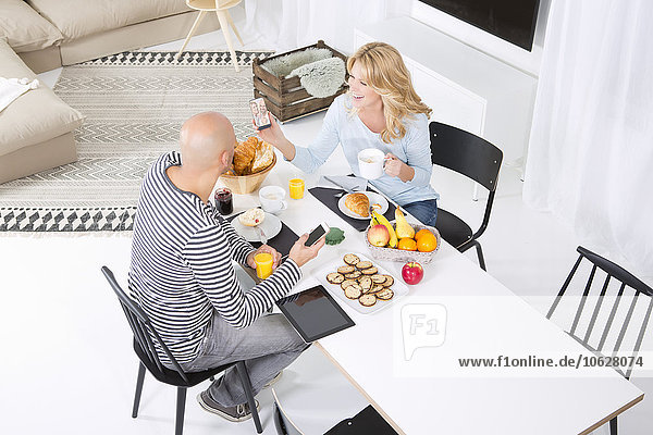 Paar am Frühstückstisch mit Smartphones