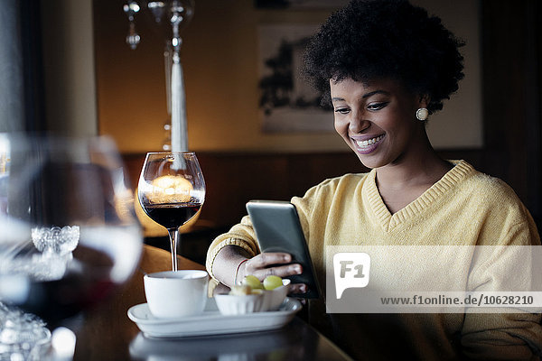 Beautiful black woman with smartphone in restaurant