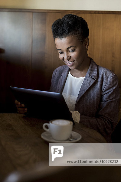 Junge Frau sitzt in einem Café mit digitalem Tablett