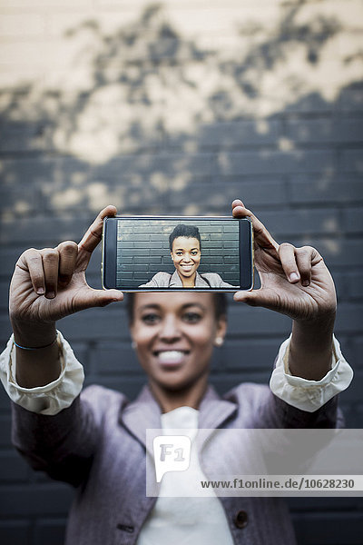 Photography of young woman taking a selfie on display of smartphone