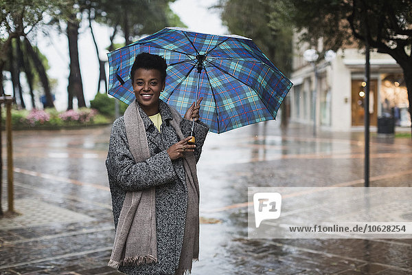 Italien  Grado  lächelnde Frau mit Regenschirm an einem regnerischen Herbsttag