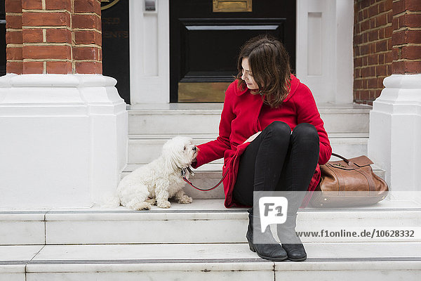UK  London  junge Frau auf der Treppe neben ihrem Hund sitzend