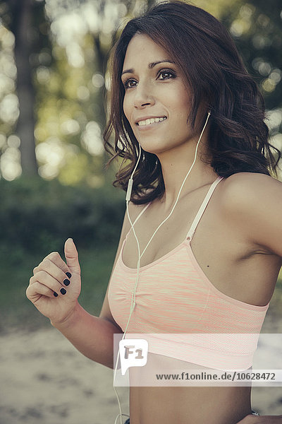 Portrait of smiling woman with earphones jogging