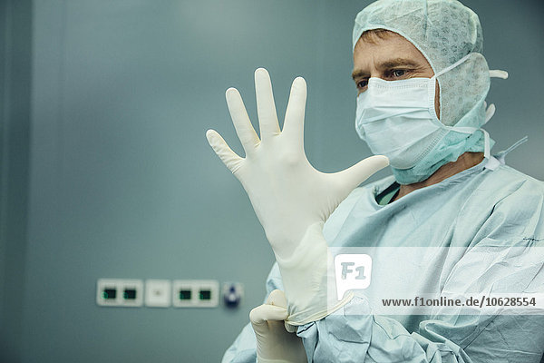 Chirurg zieht Operationshandschuhe an