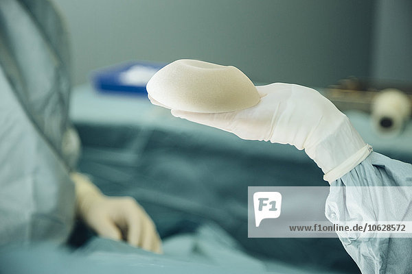 Hand haltendes Silikonimplantat während der Operation