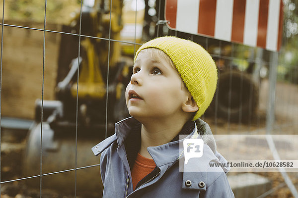 Portrait des kleinen Jungen mit gelbem Wollhut vor der Baustelle