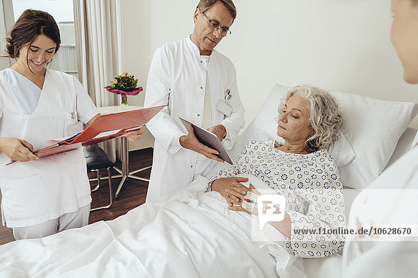 Seniorin im Krankenhaus mit Ärzten an ihrem Bett bei der Visite