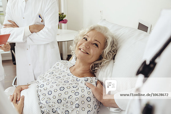 Senior woman in hospital talking to doctors  smiling