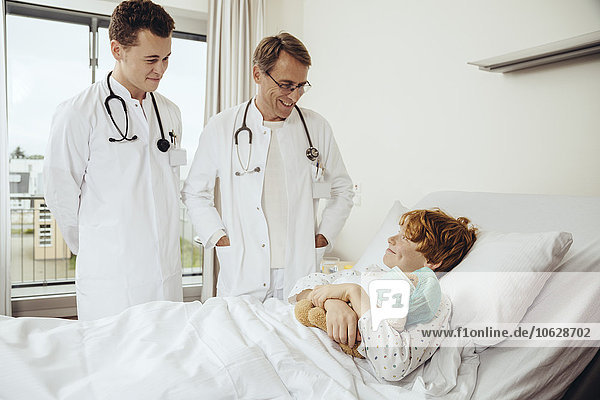 Doctors visiting boy at hospital bed
