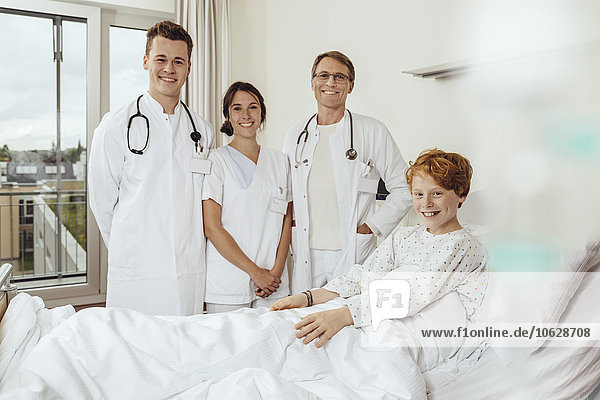 Doctors in hospital standing by bed of sick boy