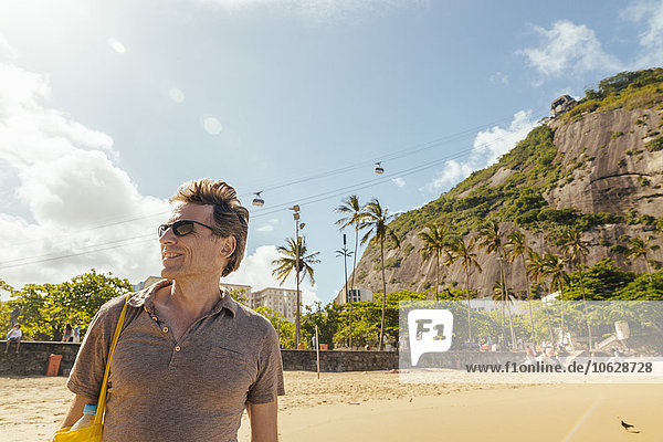 Brazil  Morro da Urca behind a male tourist on Praia Vermelha in Rio de Janeiro