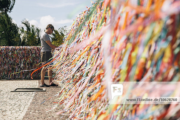 Brazil  Arraial d'Ajuda  man standing in front of wall with ribbons for quincentenary of Portuguese in Brazil