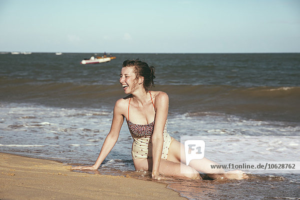 Brazil  Bahia  laughing woman sitting at seafront