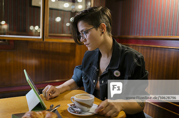 Young woman sitting in a coffee shop using digital tablet