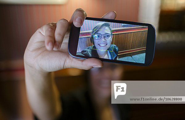 Foto auf dem Display eines Smartphones einer jungen Frau  die einen Selfie nimmt.