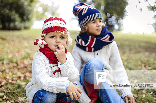 Porträt des blonden kleinen Jungen und seines Bruders im Hintergrund in modischer Strickmode im Herbst