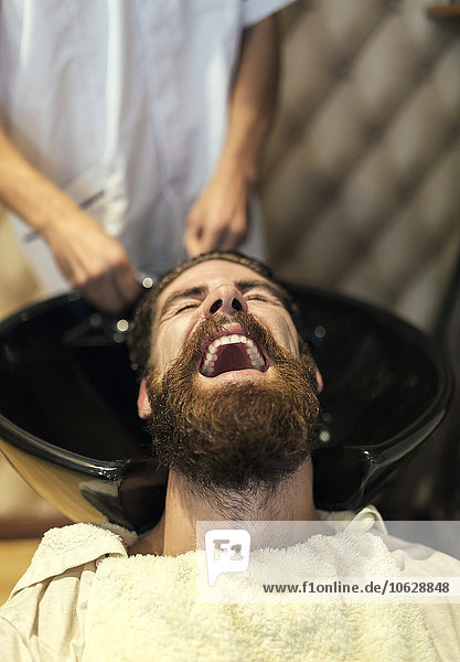 Friseur waschen Haare eines Kunden mit offenem Mund