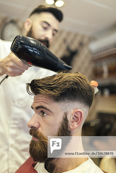 Barber blow-drying hair of a customer
