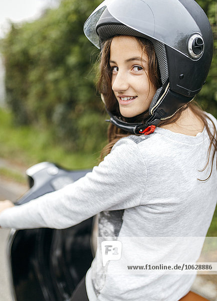 Porträt eines lächelnden Mädchens mit Motorradhelm auf einer Vespa sitzend