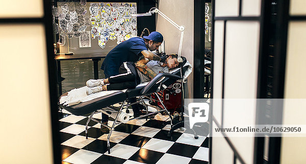 Woman receiving tattoo in tattoo studio