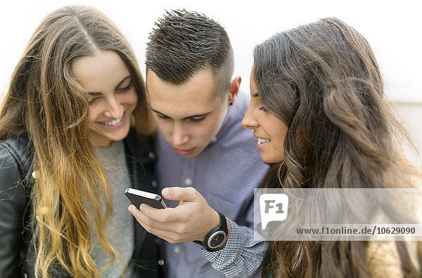 Drei Freunde schauen zusammen aufs Handy