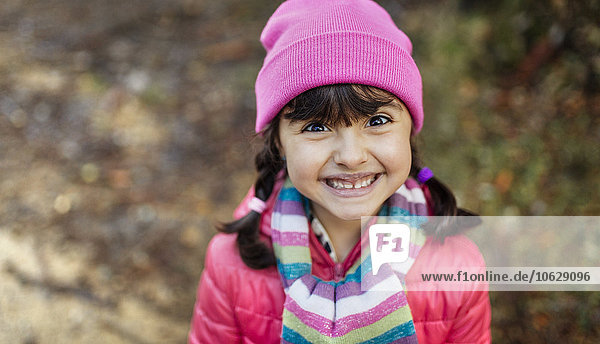 Porträt des grinsenden Mädchens mit Mütze und Schal im Herbst
