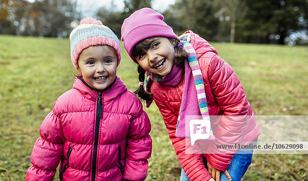 Porträt von zwei lächelnden kleinen Mädchen auf einer Wiese im Herbst