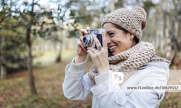 Glückliche Frau beim Fotografieren im Wald