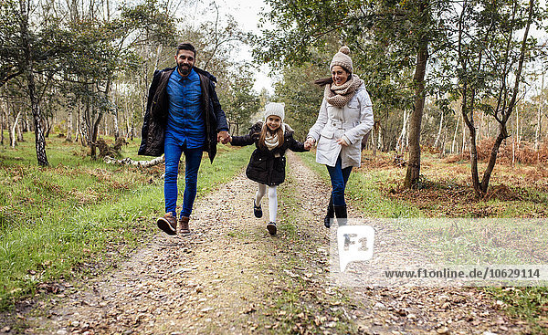 Happy parents with daughter walking on forest path