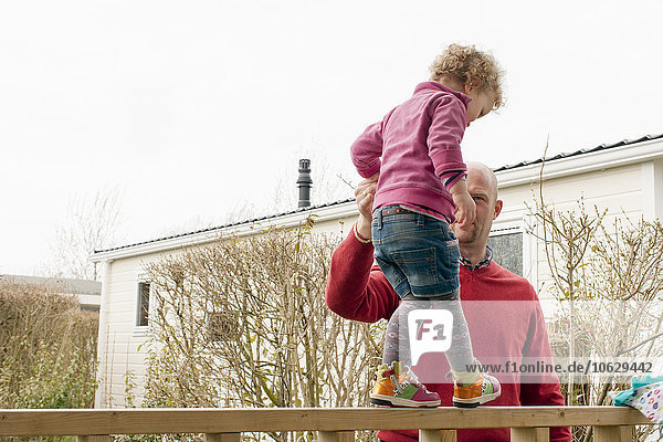 Vater hilft der kleinen Tochter beim Balancieren auf dem Balkon