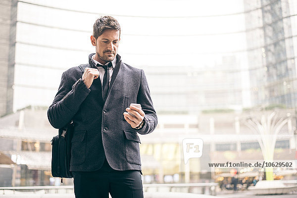 Italy  Milan  portrait of businessman looking at his smartphone