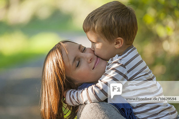 Kleiner Junge  der seine glückliche Mutter umarmt und küsst.