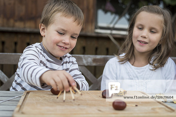 Two children tinkering with chestnuts