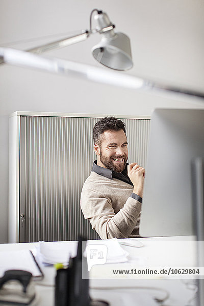 Happy man in office sitting at desk