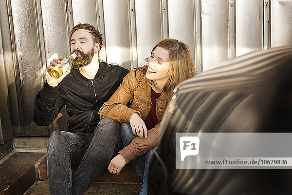 Glückliches Paar mit Bierflasche zum Entspannen in der Garage