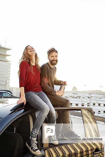 Glückliches Paar sitzt auf dem Autodach