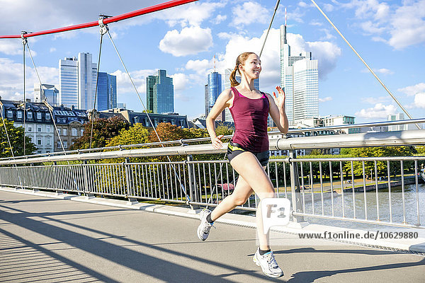 Deutschland  Frankfurt  junge Frau beim Joggen auf der Brücke