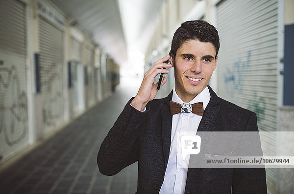 Young man on the phone wearing jacket and a wooden bow tie
