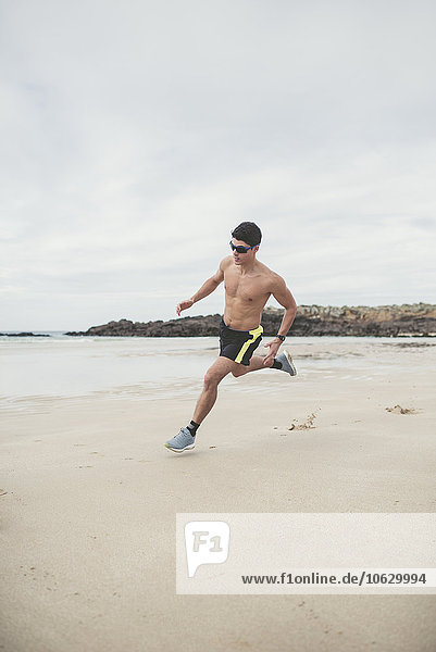 Spanien  Ferrol  ein junger Mann  der schnell am Strand rennt.