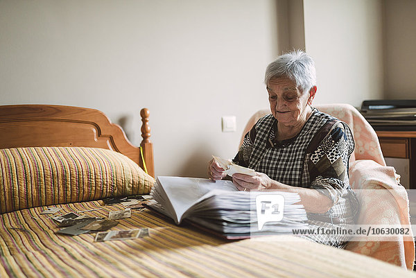 Seniorenfrau  die alte Fotos ihrer Kindheit zu Hause anschaut.