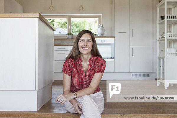 Mature woman sitting on kitchen steps  looking confident
