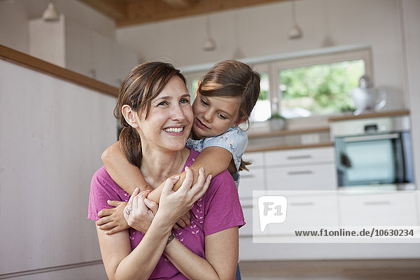 Mother and daughter sitting smiling in kitchen