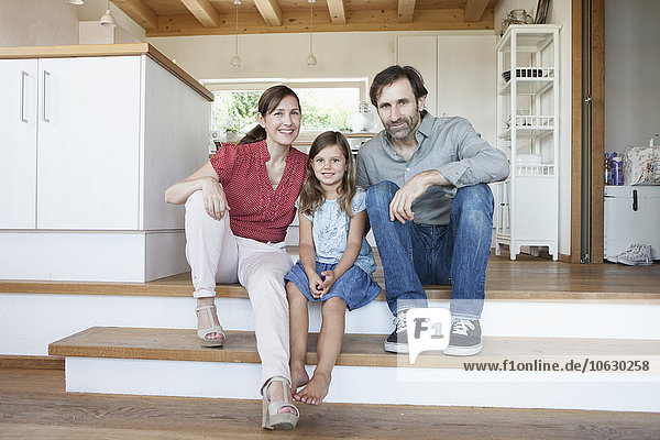 Fröhliche Familie sitzt auf Küchenstufen